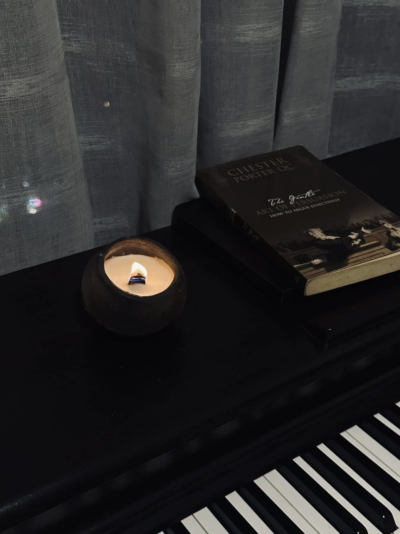 Nến gốm đang cháy trên đàn piano bên cạnh cuốn sách